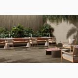 Placa gresie imitatie lemn Decor Delconca Nabi Brown 20x120 cm – ambient terasa, terasa exterioara cu masa lunga, canapea, plante verzi, pe pardoseala