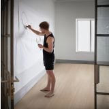 Parchet SPC Kahrs Perception - Click 6 mm – ambient living, camera goala cu parchet deschis, barbat deseneaza pe perete, pe pardoseala