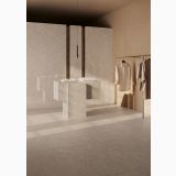Lastra HMB Gresie Taj Mahal Pure Lucios 120x278 cm – ambient comercial, showroom cu insula gresie si haine expuse, pe pardoseala si perete