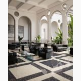 Gresie Inclusioni Clasic Avorio Mat 120x120x1.2 cm – ambient living, living elegant cu canapele negre si pardoseala terrazzo geometrica