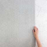 Gresie Limestone Grey Riga 60x120 cm – detaliu, mana tactila pe textura riata gri langa marmura